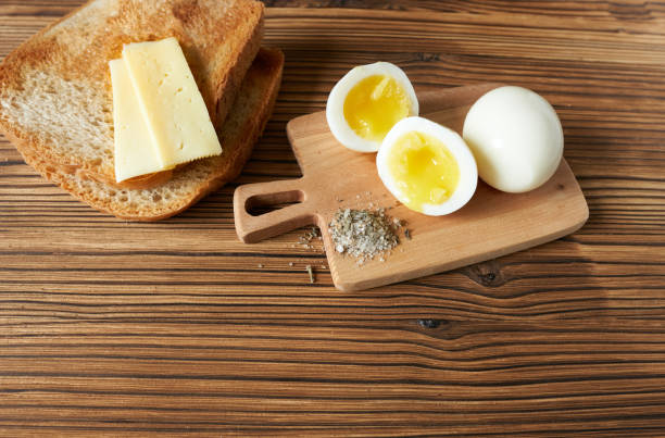 istock Boiled eggs, cheese and bread on wooden background. Top view 1487425942