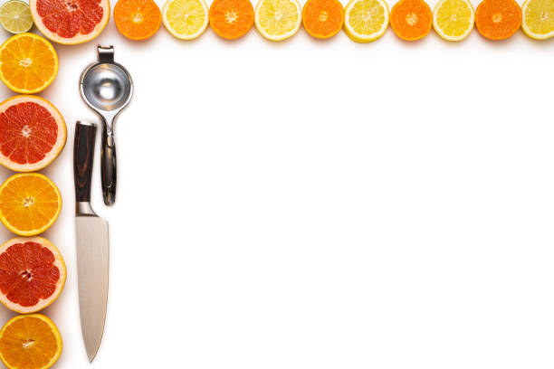 Concept for fresh, fruity and juicy fruit. Top view. Fresh sliced and halved citrus fruits, a lemon squeezer and a kitchen knife on a white background.