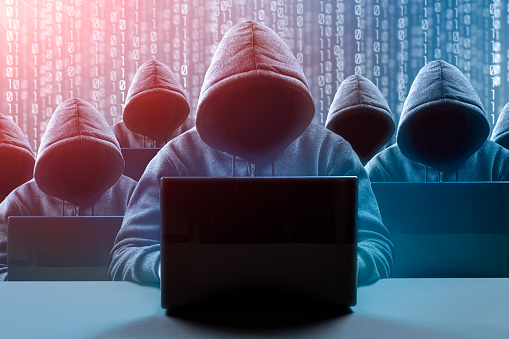 Dangerous hooded group of hackers. Internet, cyber crime, cyber attack, system breaking and malware concept. Dark face. Digital binary code on background. Malware, phishing and theft concept.
