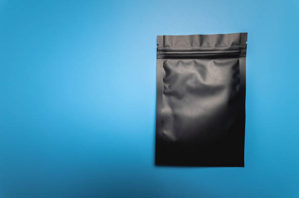 istock Mockup of a black packaging for coffee beans, lying on the table, packaging on a blue background. Tea bag template, gusset stabilo pack, for design, drawing, branding. View from above 1487428833