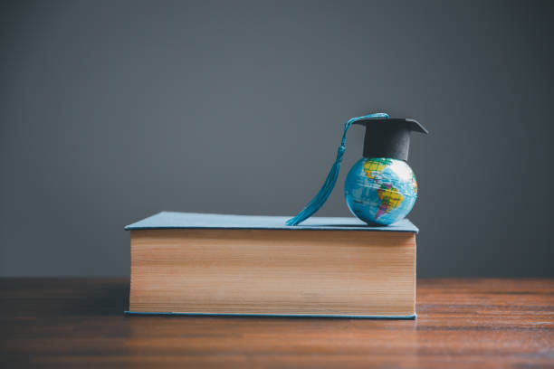 istock Graduate Studies or Studying KnowledgeLearn Abroad Concept Graduate Open Textbook with Maps Simulating. 1487430028