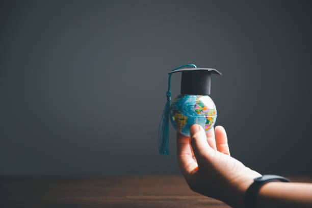 istock Graduate Studies or Studying KnowledgeLearn Abroad Concept Graduate Open Textbook with Maps Simulating. 1487430032