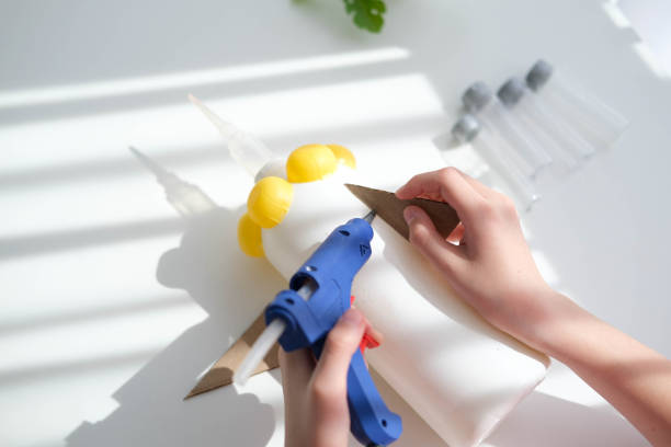 istock Step-by-step instructions for making crafts from improvised materials. Handmade at school craft rocket for the day of cosmonautics. The child is gluing parts to a plastic bottle. Step 10 1487430822