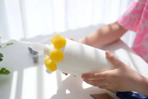 Step-by-step instructions for making crafts from improvised materials. Handmade at school craft rocket for the day of cosmonautics. The child is gluing parts to a plastic bottle. Step 11