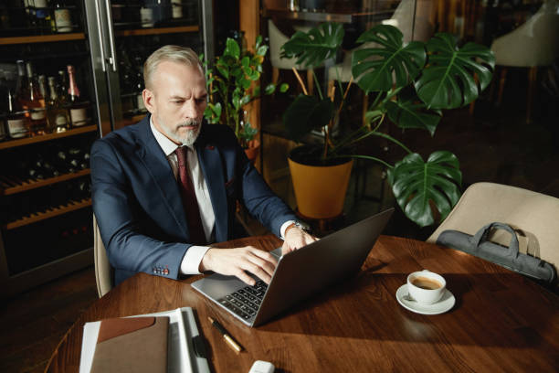 istock Serious businessman working on laptop in cafe 1487434299