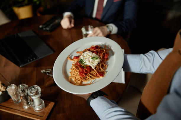 istock Waiter serving pasta to customer 1487434369