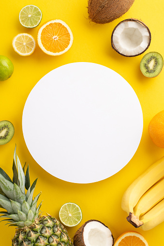 Keep it fresh and stylish this summer with this top view flat lay photo of fresh orange, lemon, lime, and pineapple coconut set against a sunny yellow background with an empty circle for your text