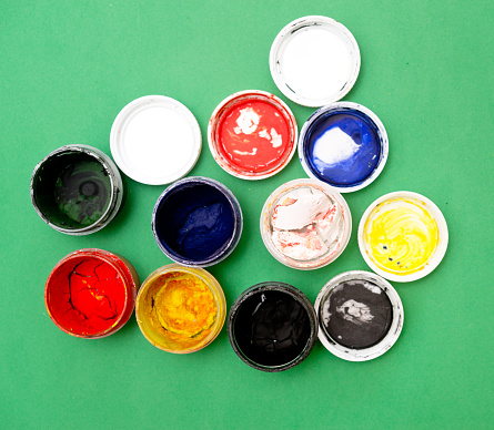 Tiny sample paint cans during house renovation, process of choosing paint for the walls, different green, blue and beige colors, color charts on background