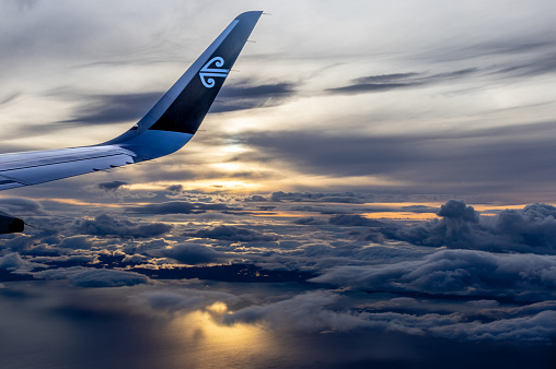 Wellington, New Zealand  - April 20, 2023: An Air New Zealand Aircraft Wing in the sky at sunset flying between Wellington and Christchurch on a national flight between cities.