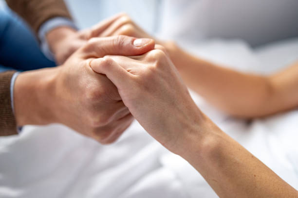 uomo che tiene la mano della donna nel letto d'ospedale. - holding hands human hand holding couple foto e immagini stock