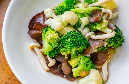 Healthy food menu, close-up stir-fried mushrooms, cauliflower, and broccoli, Thai healthy mix vegetable food on a white plate. Close-up image, view from above.
