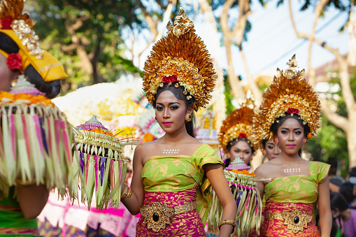 Denpasar, Bali island, Indonesia - June 11, 2016: Procession of beautiful Balinese women in traditional costumes - sarong, carry offering on heads for Hindu ceremony. Arts festival, culture of Bali.