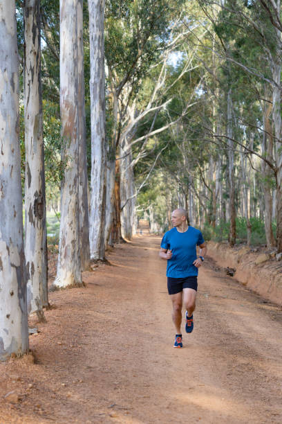 completely bald runner on gravel forest road - completely bald imagens e fotografias de stock