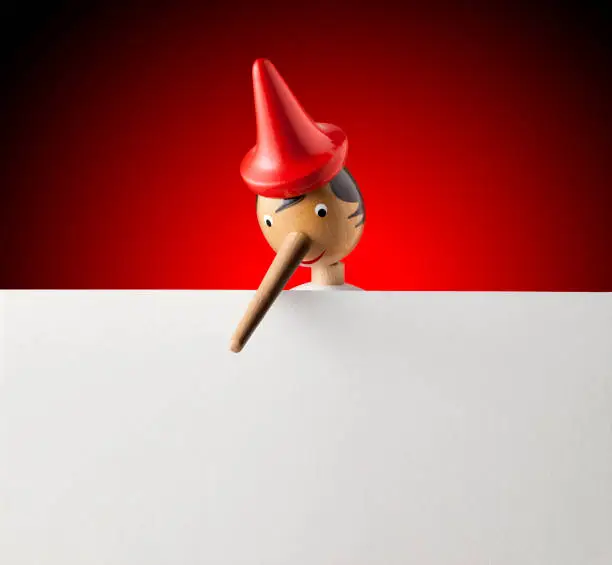 Pinocchio with a blank sheet of paper on red background.