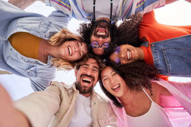 istock Multiethnic group of friends looking at camera cheerfully embracing each other. 1487449508