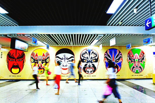 Singapore - March 25, 2023: Many people move on rush hour time with colorful Chinese mask wall background at Skytrain station in early morning. Fast movement and art with speed shutter technique.