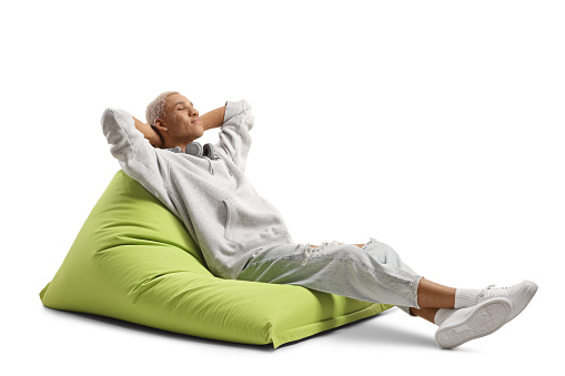 African american guy enjoying on a green bean bag armchair wide closed eyes isolated on white background
