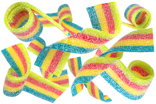 Levitation of colored jelly candy strips in sugar sprinkles isolated on white background.