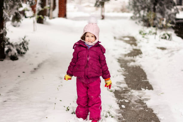 istock Smiling young girl walking down a snow-covered yard 1487453306