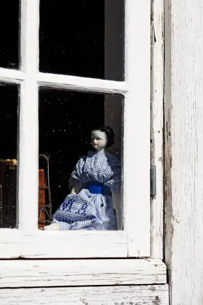 scary doll in the window of an old house