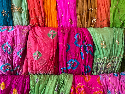 Stock photo showing a collection of ethnic, traditional clothing fabric ready for sale at a market stall.