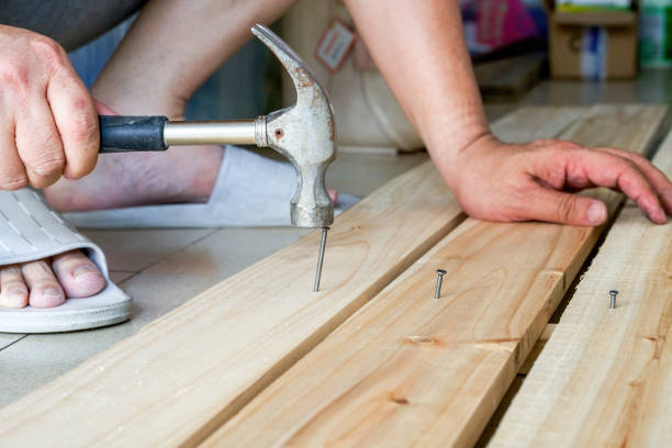 istock A worker is hitting a nail on a wooden board with a hammer 1487454689