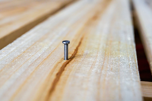 Close-up of an iron nail nailed to a wooden board