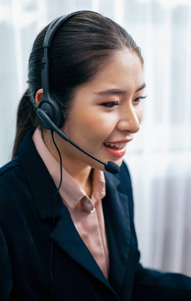 istock Enthusiastic asian call center with headset and microphone working on her laptop 1487455027