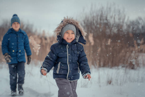 istock Boys run and laughing in snow forest. 1487455040