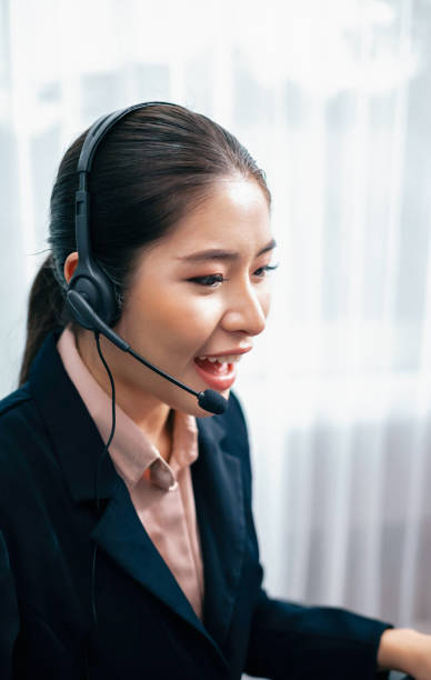 istock Enthusiastic asian call center with headset and microphone working on her laptop 1487455058
