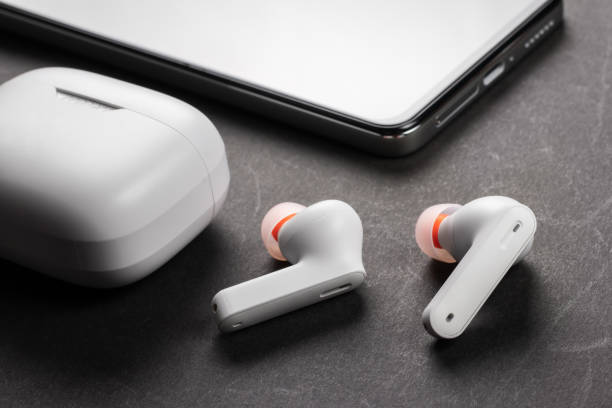 istock Wirelsss white headphones with case and smartphone on dark background 1487455691