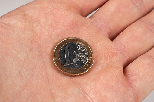 1 Euro coin held in palm close up.
