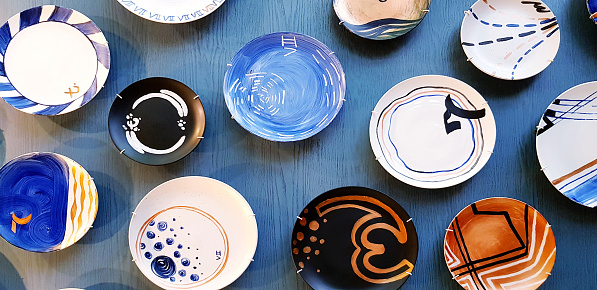 Colorful group of dish or plate decorate on blue wooden wall background. Dishware, Decorative, Design and Art object concept