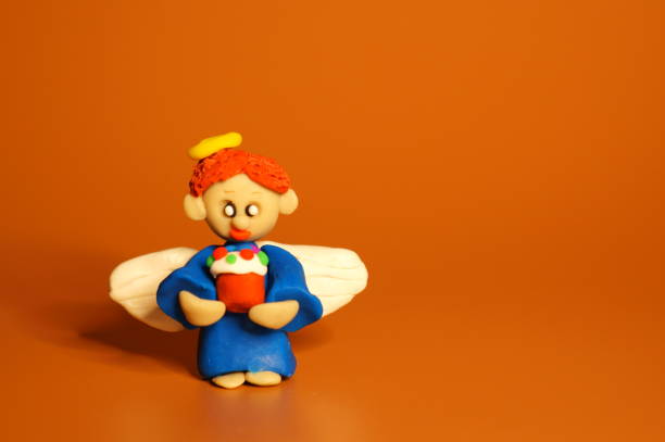 A little angel made of plasticine with a toy Easter. Bright colored background.