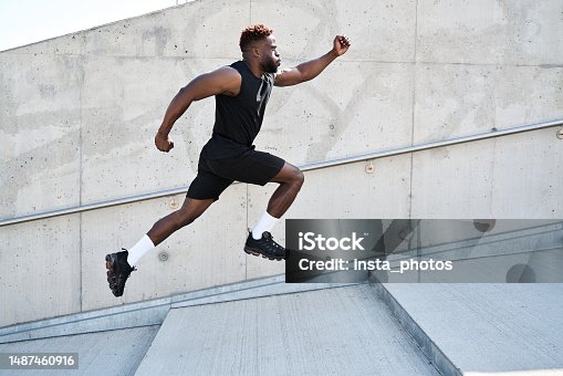 istock Confident strong fit sporty young black man running along urban wall outdoors. 1487460916
