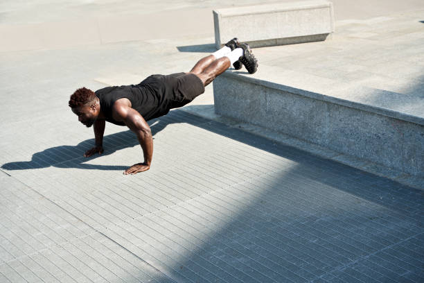 istock Fit sporty young black man doing push ups exercise in urban park. 1487460945