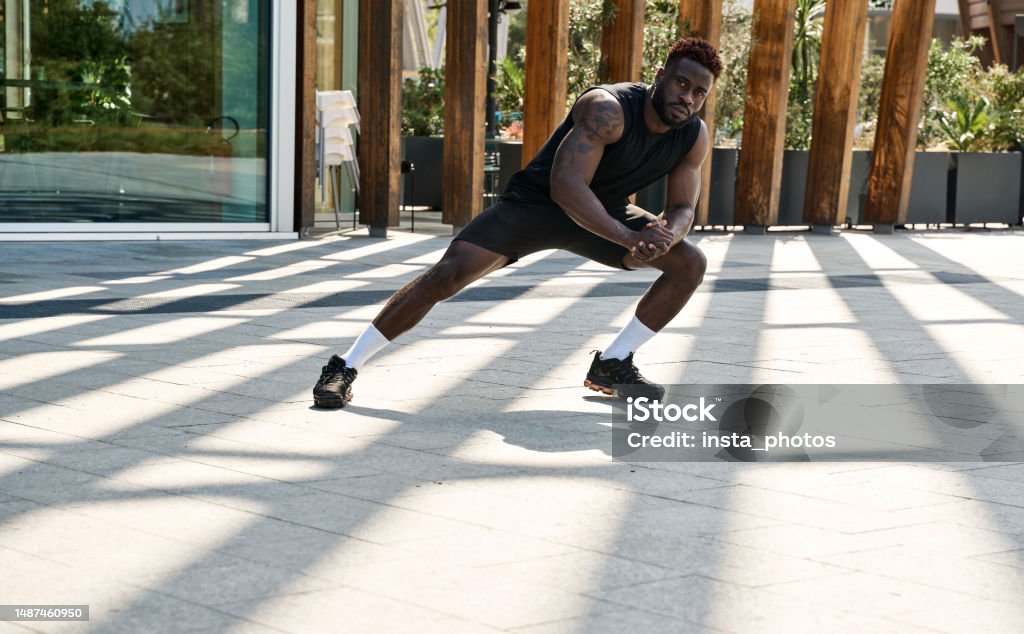 Fit sporty young black man doing warm up exercises in workout park. Fit sporty young black man doing warm up exercises in workout park. Strong healthy African ethnic guy bodybuilder doing sport fitness street workout training in outdoor gym. 25-29 Years Stock Photo