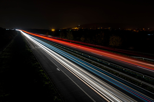 Cars light trails on a straight highway at sunset. Night traffic trails, Motion blur, Night city road with traffic headlight motion.