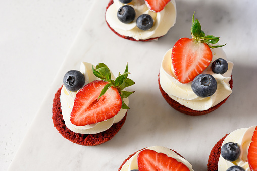 Tasty treats and bites of red velvet with whripped cream and strawberry on white background. Healthy 4th of July snacks for kids. Easy item to serve at Patriotic party for Independence Day.