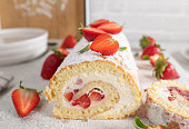Sponge cake with strawberries and whipped cream rolled up to a swiss roll