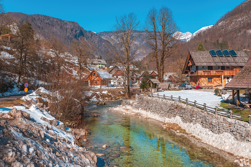Stara Fuzina, Slovenia - February 21, 2023: River Mostnica flowing through typical Slovenian Alpine village located in the Triglav National Park with many cultural and natural landmarks