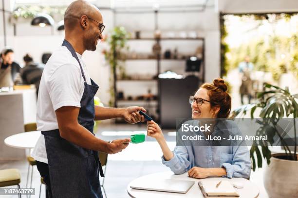 Woman Handing Her Credit Card To Make A Payment In A Cafe Stock Photo - Download Image Now