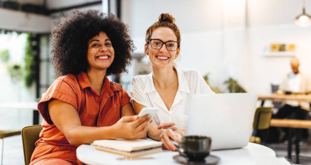istock Team building over coffee: Two happy women working in a cafe 1487463815