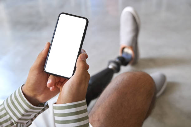istock Amputee man with leg prosthesis sitting on sofa at home using phone. 1487463833