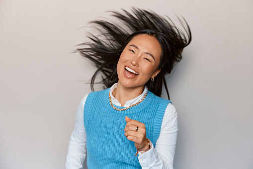 Wild, dancing and Asian woman in a studio with comic, freedom and energy dance. Laughing, celebration and party music with a excited female with a happy smile and crazy feeling from gen z youth