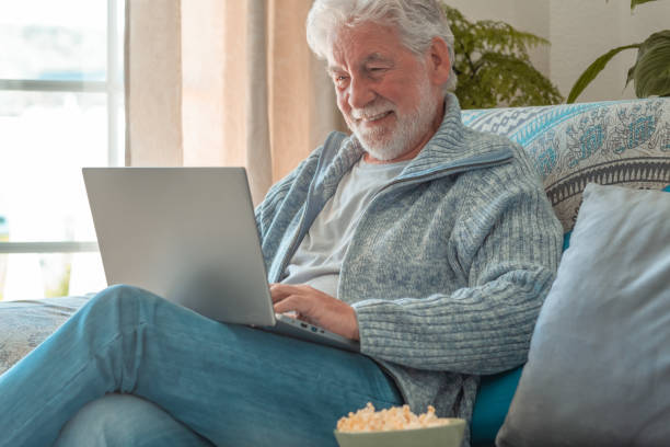istock Happy elderly 70s man seated on sofa video chatting by laptop, older generation and modern tech application easy usage concept 1487468256
