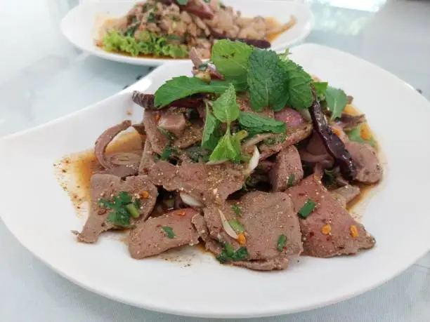 Photo of The favorite dish of Thailand, spicy pork liver salad (Tub wan) served with mint leaves and fresh vegetables.