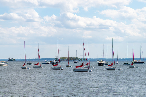 Greenwich, CT-August 2022; View over the water of Greenwich Harbor and Long Island sound with anchored sail boats and Beach Island recreational area in the background