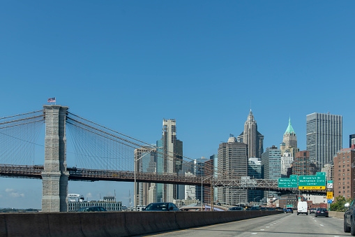 New York City, NY, USA-August 2022; Drivers view in southerly direction over a busy FDR Drive at Lower East Side with Brooklyn Bridge and Financial District in background