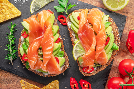 Salmon toasts - bread with salmon slices and avocado spread, guacamole and tortilla chips. Top view.